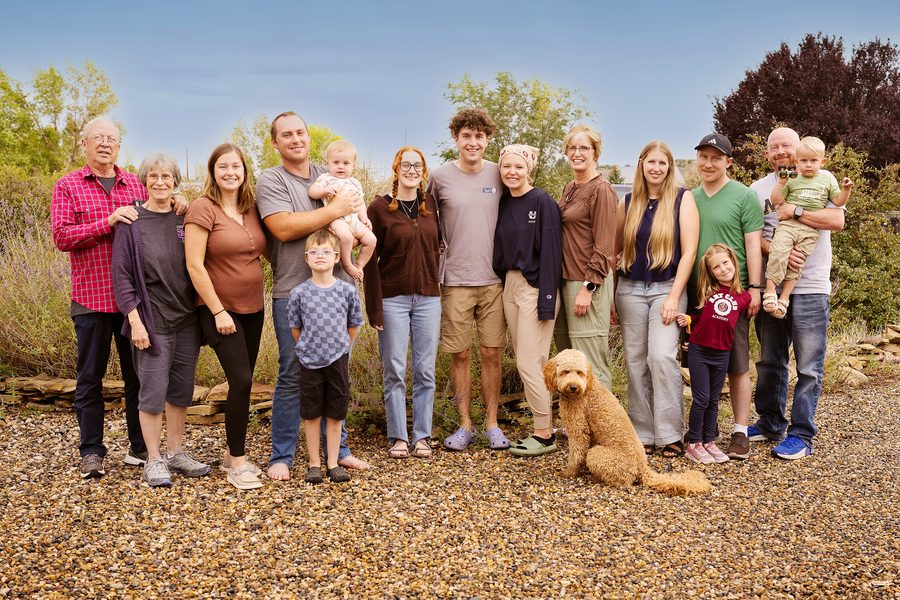 Three generations of a family and their golden doodle on a gravel yard