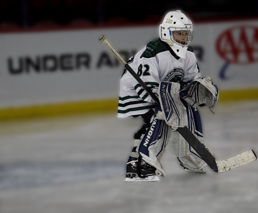 Youth hockey goalie in a white away jersey, number 82, set in the crease